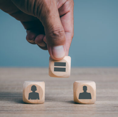 Man's hand is placing wooden blocks on the table, gender equality concepts, human discrimination, liberties and gender issues, reducing social inequality.