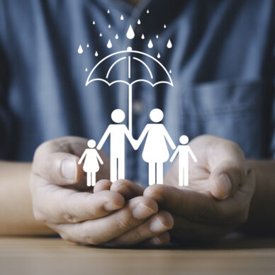 Businessman hands protecting a family under an umbrella symbol representing insurance safety security care support and risk management for health life and family protection concept.